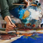 Top view of attractive woman hands drawing amazing picture on canvas in modern cozy art workshop